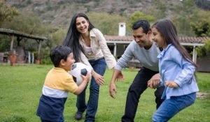 Happy Latin American family playing football outdoors and having fun together - lifestyle concepts